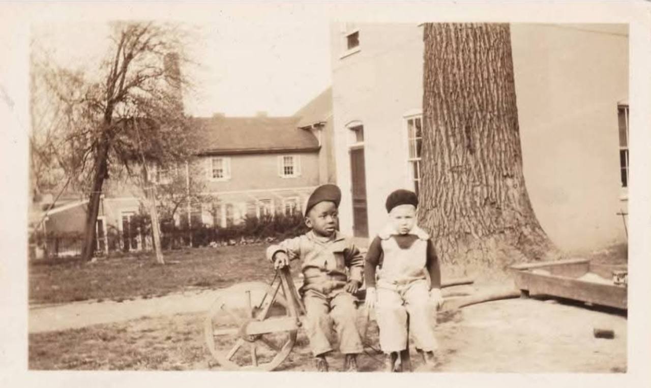 Historical family collection photograph of two children beside a tree